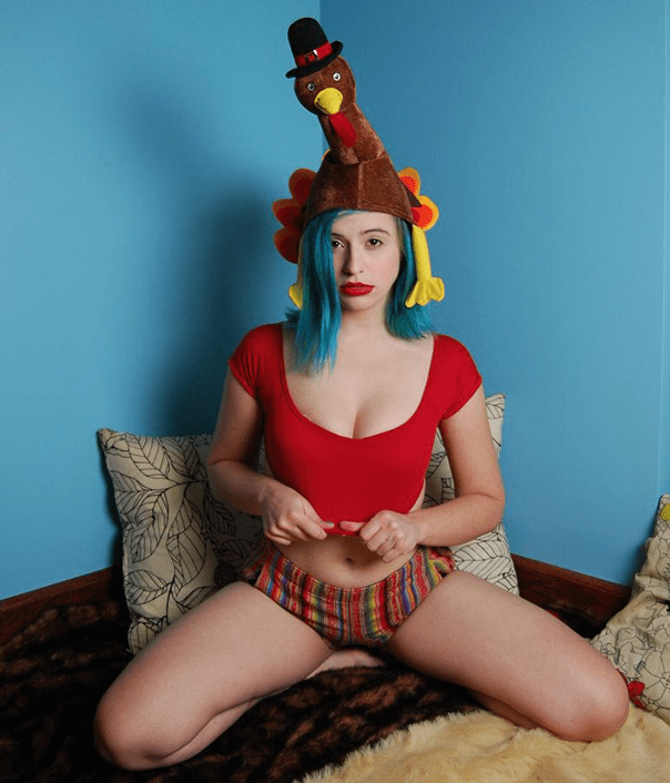 person with in bed with red shirt, underwear, and turkey hat on